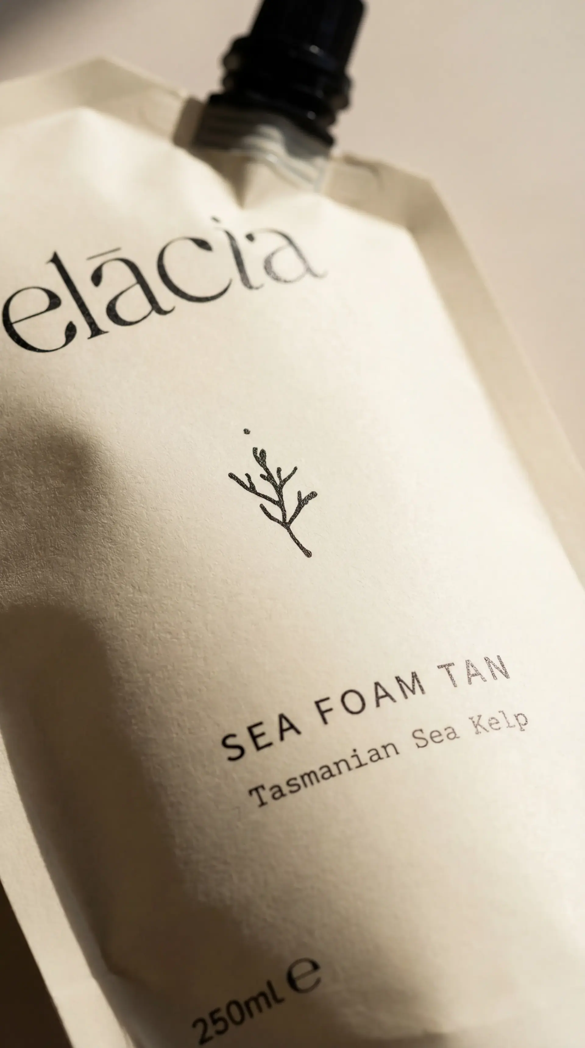 Elacia Sea Foam Tan refill pouch, close-up in warm daylight.