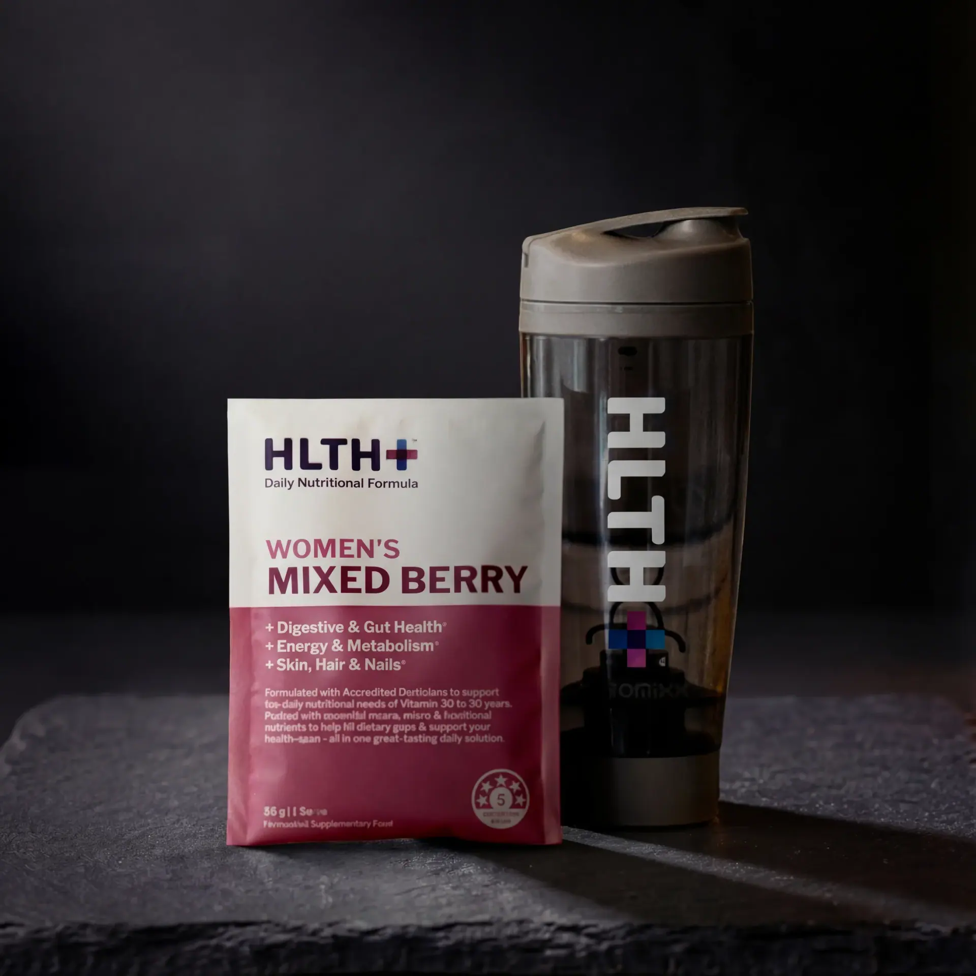Hlth+ Mixed Berry sachet next to a black branded shaker on dark slate